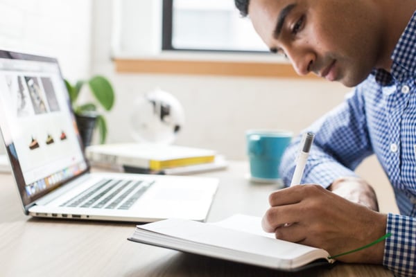 businessman using ballpoint men next to laptop