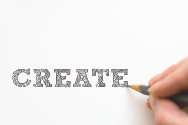 closeup of hand over white and black board that says create