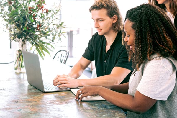 man working on laptop while woman takes notes