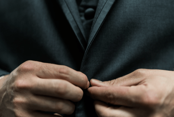 person holding black suit jacket button