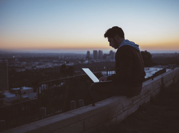 personal on laptop sitting on roof