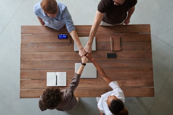 photo of people doing first bump next to table