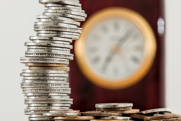 silver and gold coins in front of a clock.