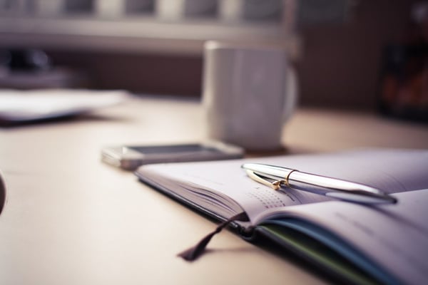 silver pen on top of notebook of calendar