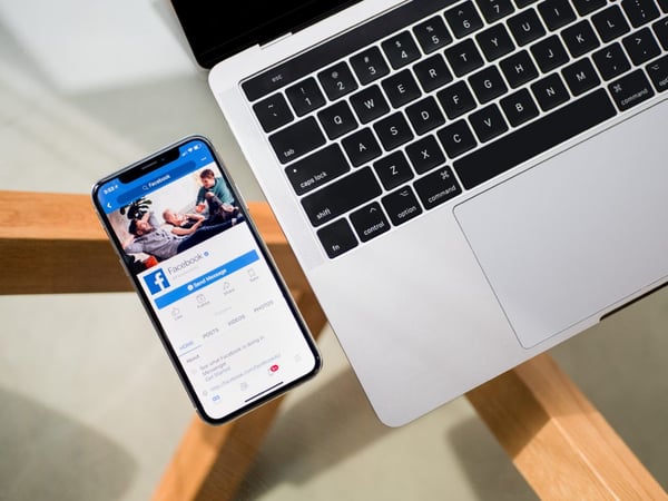 facebook on iphone next to laptop