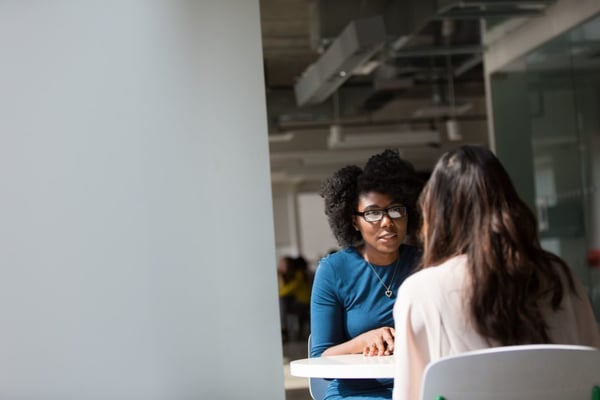 woman wearing blue talking to another woman